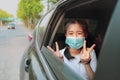 Asian teenager wearing protection mask sitting in car hand sigh for victory