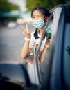 Asian teenager wearing protection mask sitting in passenger car and hand sign victory