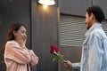 Asian teenager woman surprised and smiling at boyfriend gives red rose flowers at dinner in valentine day. young happy couple love Royalty Free Stock Photo