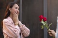 Asian teenager woman surprised and smiling at boyfriend gives red rose flowers at dinner in valentine day. young happy couple love Royalty Free Stock Photo