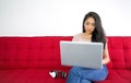 Asian teenagers use the application to connect headphone to laptop computer on the red sofa to relax in the living room. Enjoy Royalty Free Stock Photo