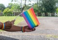 Asian or Thai gay hands wearing lgbtq+ wirstband and holding rainblow flag as sign to protect and support gender diversity on