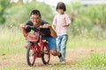 Asian Thai kid boys and girls is brother and sister playing and exercising in the outdoor garden red bicycle boy girl running and Royalty Free Stock Photo