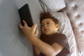 Asian thai kids lying on the bed and watching plays in the smartphone Royalty Free Stock Photo