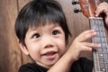 Asian Thai Little Boy Holding The Ukulele in Hand. Royalty Free Stock Photo