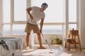 Asian Thai man using mop for cleaning floor in living room apartment, Man do household chores, housework concept. Royalty Free Stock Photo