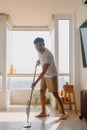 Asian Thai man using mop for cleaning floor in living room apartment, Man do household chores, housework concept. Royalty Free Stock Photo