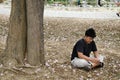 Asian thai men sit on floor and reading book under pink trumpet tree Royalty Free Stock Photo