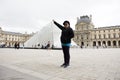 Asian thai old woman travel and posing for take photo at Louvre Pyramid at Musee du Louvre