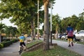 Asian thai people and foreign travelers walking jogging exercise biking bicycle on pathway around pondside in dusk time at Nong