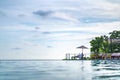 Asian Thai teenager female white dress relaxes on the wooden bed beside infinity pool with sea beach behind at South-East of