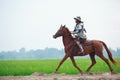 Asian Thai Warrior in traditional armor suit riding horse in rural farm background. Vintage Retro war costume concept Royalty Free Stock Photo