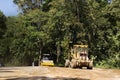 Thai workers use heavy machinery motor grade and vibratory roller working made and build road on mountain in Chiang Rai, Thailand