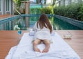 Asian Thai young woman lying and relaxing on bed near swimming pool in spa salon with a drink glass, beauty and body care concept Royalty Free Stock Photo