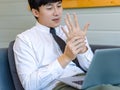 Asian tired overwork male businessman employee in business outfit sitting on sofa working with laptop computer holding hand Royalty Free Stock Photo