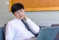 Asian tired overwork male businessman employee in business outfit sitting on sofa working with laptop computer holding hand