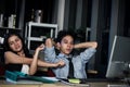 Asian tired staff officers try to relieve physical tension after work hard overtime at night in office, having overwork project Royalty Free Stock Photo