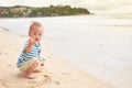 Asian toddler baby boy child on beach with dirty hands covered with wet sand, water outdoor activity on summer beach vacation with Royalty Free Stock Photo