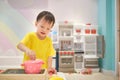 Asian toddler boy child having fun playing alone with cooking toys, kitchen set, Pretend and role play toys for young kid concept
