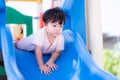 Asian toddler boy was face down to play on the blue slide. In hot day child sweats on his face. Royalty Free Stock Photo