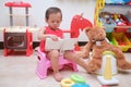 Asian toddler girl child sitting on potty and reading a book with toys & teddy bear, Potty training, Learning to use the Toilet Royalty Free Stock Photo