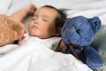 Asian toddler sleeping with teddy bear on white bed, pillow and sheet Royalty Free Stock Photo