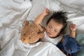 Asian toddler sleeping with teddy bear on white bed, pillow and sheet Royalty Free Stock Photo