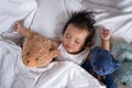 Asian toddler sleeping with teddy bear on white bed, pillow and sheet Royalty Free Stock Photo