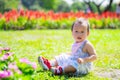 Asian Toddler 1 year old Sitting Amongst Colorful Garden Flowers. Young child sits thoughtfully on grass, surrounded by burst of Royalty Free Stock Photo