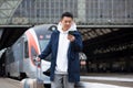 Asian tourist booking accommodation at home using mobile phone, passenger arrives by train to new city