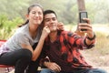 An Asian tourist couple takes selfies with their smartphones