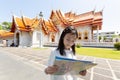 Asian tourist girl sightseeing holding map with big temple at Wa