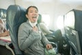 Asian tourist woman flying in times of covid19 - young happy and funny Korean girl pulling off mask breathing free on airplane