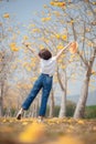 An Asian tourist woman relaxes and has freedom in the beautiful blooming yellow flower tree tunnel. Travel and Lifestyle Concept