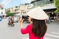 Asian tourist woman is wearing Vietnamese traditional hat and dress take a photo while walking sightseeing in Hanoi city Vietnam Royalty Free Stock Photo