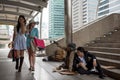 Asian tourist women with many shopping bag look down on smell homeless dirty old guy and drunk businessman in urban city. bad