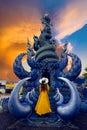 Asian tourists stand to admire a blue statue in a temple in Chiang Rai, Thailand