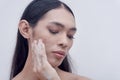 An Asian trans lady touches her face with soapy hands as she attempts to remove her makeup with a gentle facial cleanser. Royalty Free Stock Photo