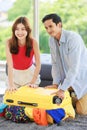 Asian traveler couple in casual vacation outfit with sunglasses and hat sitting smiling on carpet floor in living room packing Royalty Free Stock Photo