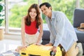 Asian traveler couple in casual vacation outfit with sunglasses and hat sitting smiling on carpet floor in living room packing Royalty Free Stock Photo