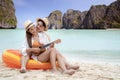 Asian traveller couple sitting and see sunset togather on the beach with longtail boat background