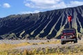 Asian traveller take a photo on the top of advanture car in bromo volcano mountain Royalty Free Stock Photo