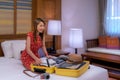 Asian traveller woman packing her travel bag on hotel bed