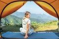 Asian traveller woman post yoga in tent on her camping