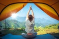 Asian traveller woman post yoga in tent on her camping