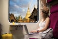 Asian traveller woman sit on the train seat and locking to out of train window with wat phra singh temple view Royalty Free Stock Photo