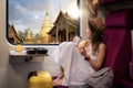 Asian traveller woman sit on the train seat and locking to out of train window with wat phra singh temple view Royalty Free Stock Photo