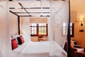 Asian tropical bedroom four poster bed white curtain and armchairs