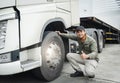 Asian Truck Driver Giving Thumb-Up and Checking Semi Truck Wheels Tires. Truck Inspection Maintenance and Safety Driving