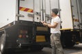 Asian truck driver holding clipboard checking container door security. Truck inspection safety and maintenance. Royalty Free Stock Photo